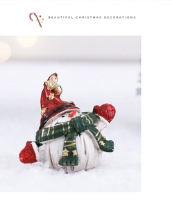 Detailed view of a miniature Christmas snowman figurine with red hat and green scarf