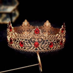 Macro shot of gold baroque crown with intricate leaf patterns and red drop gemstones