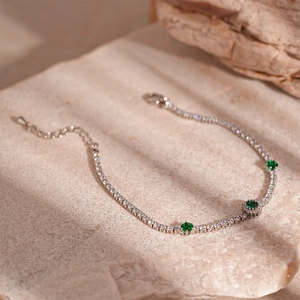 Detailed macro of tennis bracelet with emerald green zircons on natural stone base
