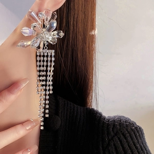 Close-up of model wearing silver crystal flower earrings with dangling rhinestone tassels
