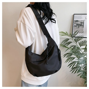 Fashionable black crescent crossbody tote bag shown on model in a casual indoor setting
