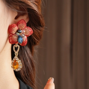Gros plan de boucles d'oreilles vintage asymétriques à fleurs rouges avec pendentifs