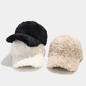 Detailed close-up of plush faux fur baseball caps in black, white, and beige colors