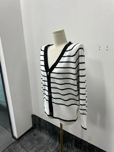 Nahaufnahme der Stricktextur und Goldknöpfe am schwarz-weiß gestreiften V-Ausschnitt Cardigan