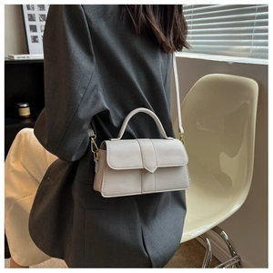 Cream white crossbody bag on a grey suit jacket, showcasing the size and style