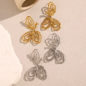 Detailed macro view of textured gold and silver butterfly earrings on a beige surface