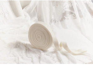 Close-up of thick white wool felt ribbon roll for Christmas DIY crafts on lace background