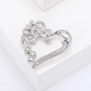 Detailed back view of heart-shaped brooch showing safety pin clasp and hollow metal frame