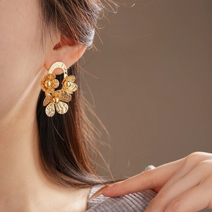 Close-up of textured gold floral stud earrings featuring three layered petals for women