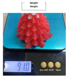 Macro view of a red pine cone candle weighing 91g on a digital scale for Christmas