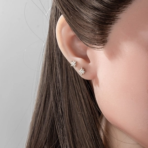 Boucles d'oreilles étoile à quatre branches en argent avec zircon portées en parure