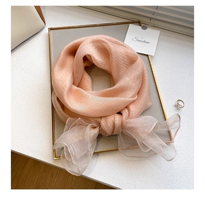 Close-up of pink silk wool blend scarf with subtle metallic thread on a golden tray