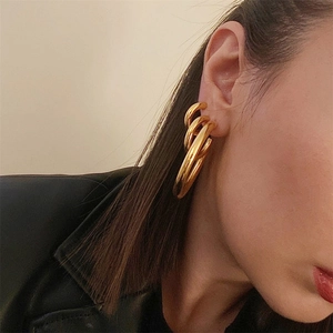 Close-up of chunky gold-plated stainless steel hoop earrings on model with high gloss