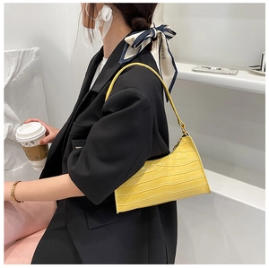 Detail of yellow crocodile pattern shoulder bag on model with black blazer