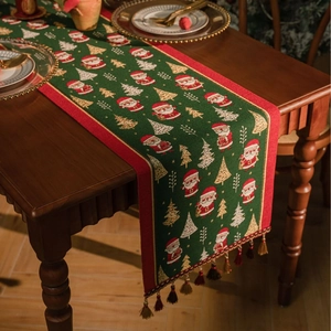 Detailed texture of green Christmas table runner with Santa motifs and gold tassels