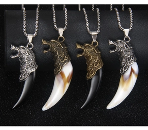 Detail of wolf tooth necklaces with silver and bronze metal wolf heads and acrylic teeth