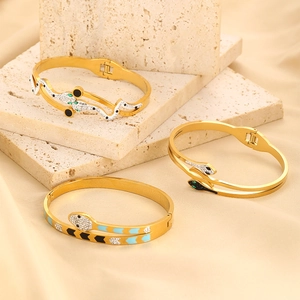 Macro shot of gold-plated snake bracelets with sparkling crystals and enamel on marble