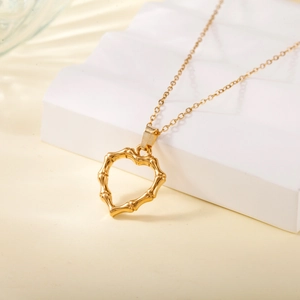 Vintage gold heart pendant necklace with bamboo texture on white geometric steps
