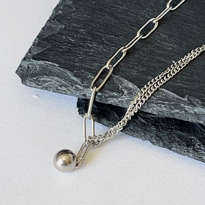 Macro shot of silver mixed chain necklace with metallic bead pendant on stone