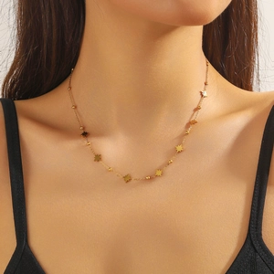 Close-up of a gold stainless steel necklace with star charms and beads on a model