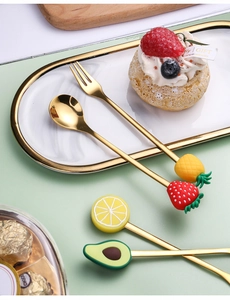 Close-up of golden stainless steel fruit dessert spoons and forks with creative handles