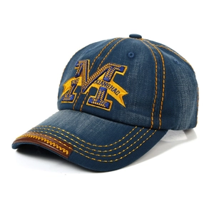 Navy denim baseball cap with yellow M embroidery and brown leather brim detail