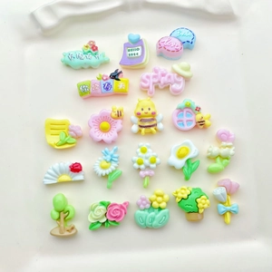 Flat lay of colorful resin charms including flowers, bees, and spring theme DIY accessories