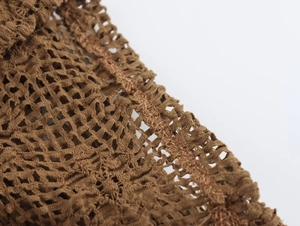 Macro shot of brown lace crochet fabric showing detailed mesh structure and stitching