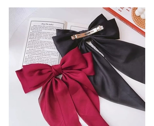 Detail of satin bow hair clips in black and wine red with metallic spring fasteners