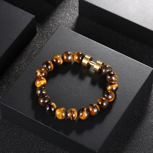 Gros plan détaillé du bracelet en œil de tigre avec haltère doré sur une boîte cadeau