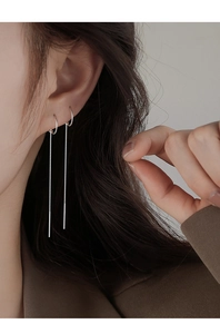 Close-up of minimalist silver long tassel threader earrings worn by a model