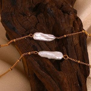 Macro shot of baroque pearls and 18K gold-plated chain on a rustic wood and fabric background