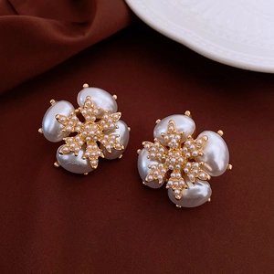 Detailed close-up of vintage gold snowflake earrings with inlaid white pearls on fabric