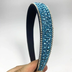Close-up of sparkling light blue rhinestones on a luxury padded headband with blue fabric