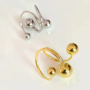 Makroaufnahme von Gold- und Silberspiralringen mit Metallkugeln auf weichem Hintergrund