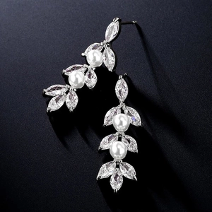 Detail van zilveren hangende oorbellen met marquise-zirkonia en witte parels op zwart