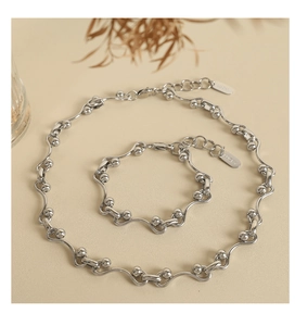 Detailed macro view of the silver wavy bar chain and the Lucky brand charm on the necklace