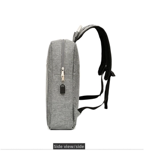 Side view of gray travel backpack showing built-in USB charging port and fabric texture