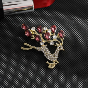 Detail of golden reindeer brooch featuring red teardrop stones and sparkling crystals