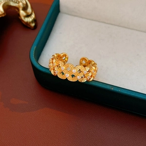 Dettaglio di un anello a croce placcato oro 18k con zirconi bianchi su scatola verde