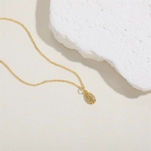 Close-up of golden oval pendant necklace with zircon stones and FASHION engraving