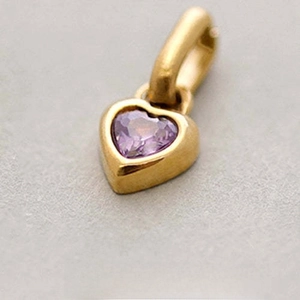 Macro view of a gold heart pendant featuring a purple amethyst stone and Juni engraving
