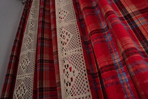 Detail of red plaid fabric with beige crochet lace trim on American style curtains