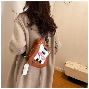 Detail of guitar-shaped crossbody bag featuring star studs and adjustable strap on a model