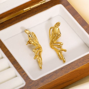 Abstract fluid wing stud earrings in 18k gold plated stainless steel on jewelry box