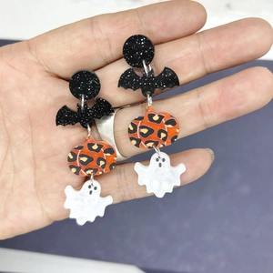 Detail of Halloween drop earrings featuring acrylic bat, leopard pumpkin and ghost charms