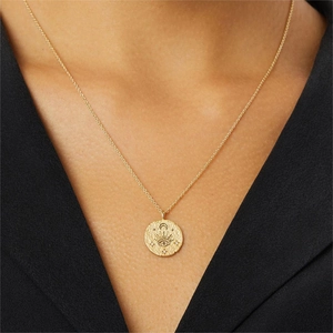 Detail of a gold coin pendant with engraved evil eye, crescent moon and star patterns