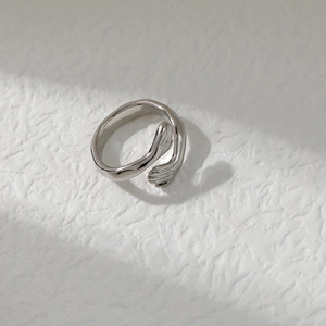 Minimalist silver hug ring with unique palm design on textured white background