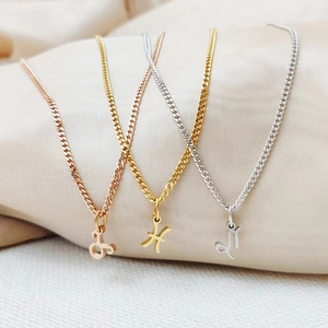 Close-up of three zodiac symbol necklaces in rose gold, gold and silver on silk fabric