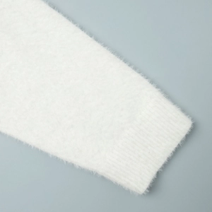Close-up of white plush knit sweater sleeve with ribbed cuff texture and soft fuzzy fibers